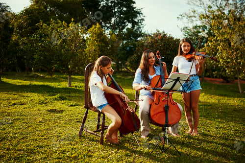 Preview: Shot of a beautiful mother playing instruments with her adorable daughters outdoors