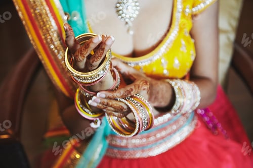Preview: Indian bride wear saree putting the bracelets (bangle) on hand with mehndi, close-up