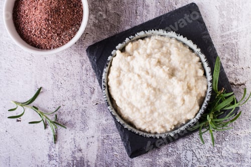 Preview: Tahini sauce from sesame seeds in a bowl and ingredients for cooking on the table. Top view. Closeup