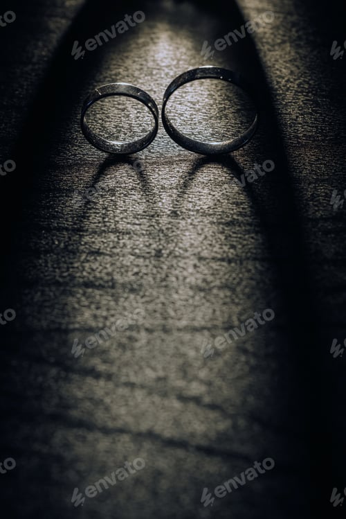Preview: Close-up of two gold wedding rings on a black background