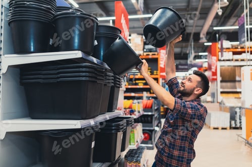 Preview: a man in a construction hypermarket chooses construction buckets