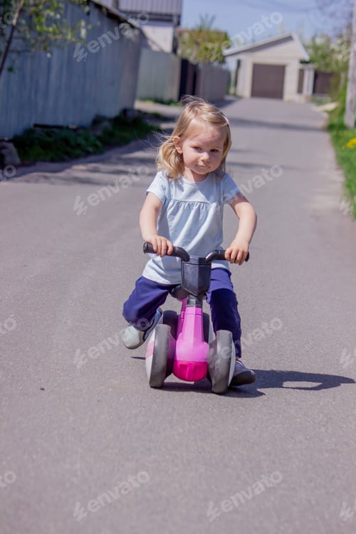 Preview: Little girl riding a balance bike. nature.