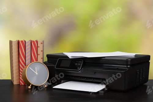 Preview: Stack of books and home printer against blurred background