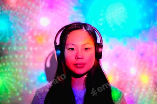 Preview: Asian woman in headphones under glowing neon colors