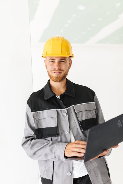Preview: Smiling engineer in work clothes and yellow hardhat happily look