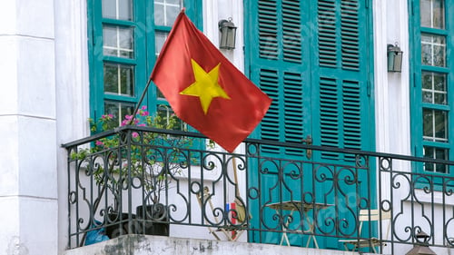 Preview: A red Vietnamese national flag waves on balcony house with blue doors and window