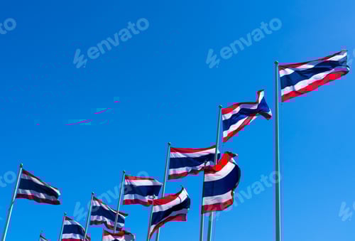 Preview: Many of Thailand flag waving on top of flagpole against blue sky. Thai flag was drawn to top