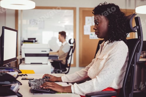 Preview: Side view of businesswoman working on computer at desk