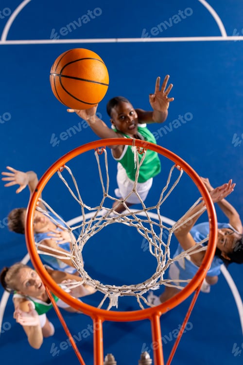 Preview: Playing basketball, girl in green jersey jumping to score basket