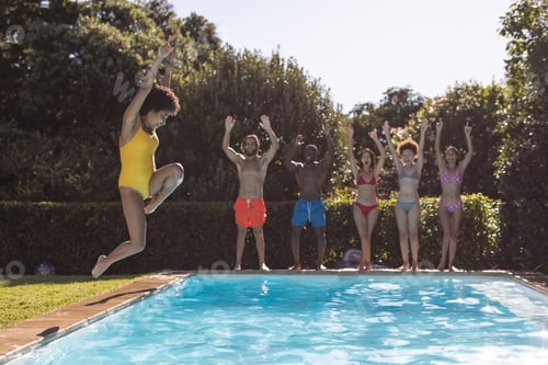 Preview: Diverse group of friends having fun and jumping into water at a pool party