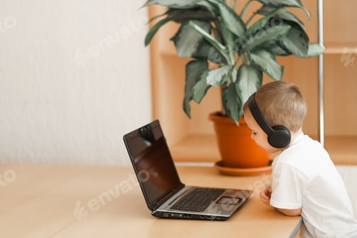 Preview: A boy with headphones is sitting in front of a laptop