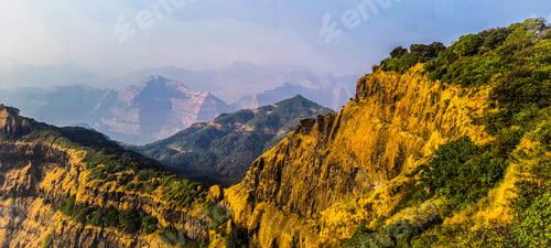 Preview: A landscape featuring lush yellow bushes and trees set against backdrop of a mountain range