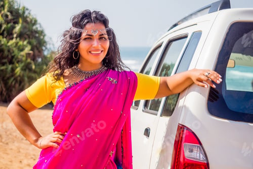 Preview: relaxed indian woman in a traditional pink sari and costume jewelry