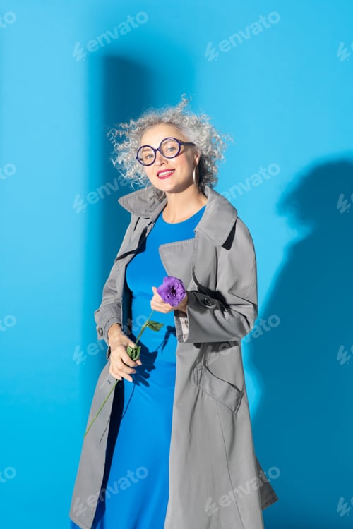 Preview: Beautiful mature woman holding little purple flower