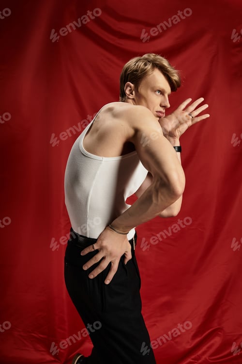 Preview: Young alluring man expressing modern masculinity with confidence against a red backdrop
