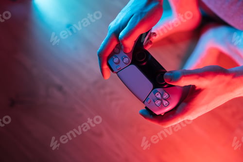Preview: Man hands with game controller in neon light, top view