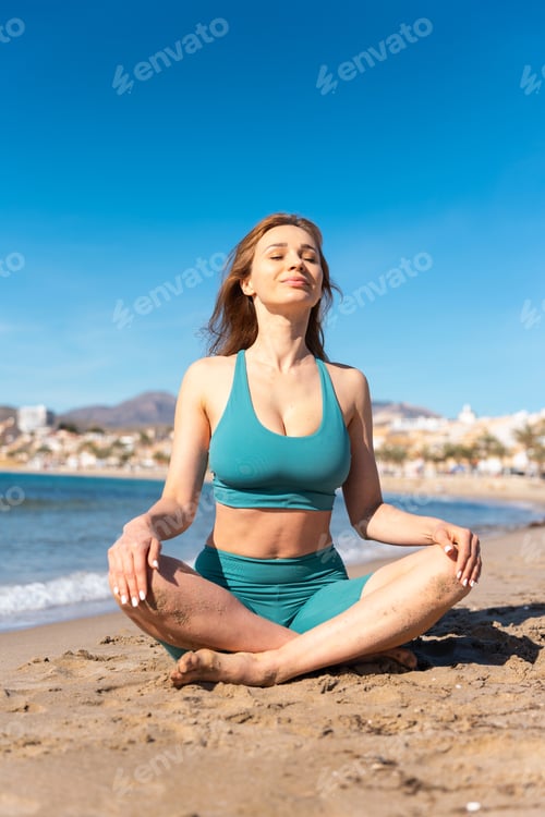 Preview: Woman practicing yoga asana and breathing on the beach in spain