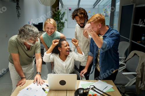 Preview: Group of colleagues at the office raising their arms in celebration a good new