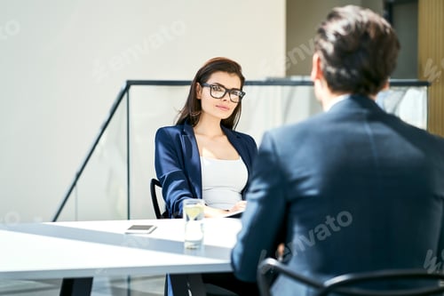 Preview: Businesswoman and businessman talking at desk in modern office