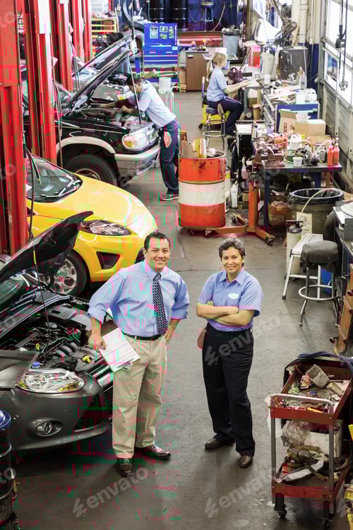 Preview: Portrait of owner of auto repair shop talking with female mechanic as others work in background