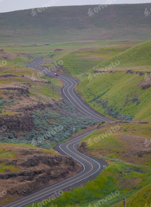 Preview: a highway in the mountains with some cars on it and a hill behind it