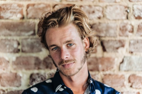 Preview: Portrait of confident blond man at brick wall