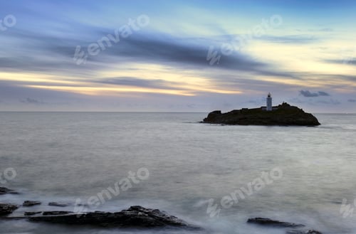 Preview: Picturesque Lighthouse on Rocky Island at Sunrise