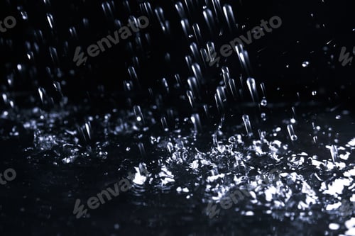 Preview: Heavy rain falling down on ground against dark background, closeup