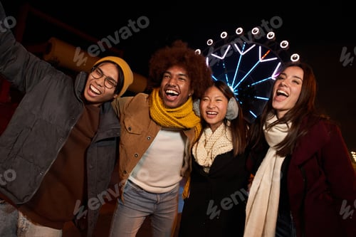 Preview: Night Portrait of mixed race group of happy colleagues having fun in winter clothes.