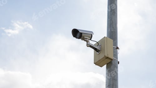 Preview: Surveillance camera mounted on a pole with sky background.
