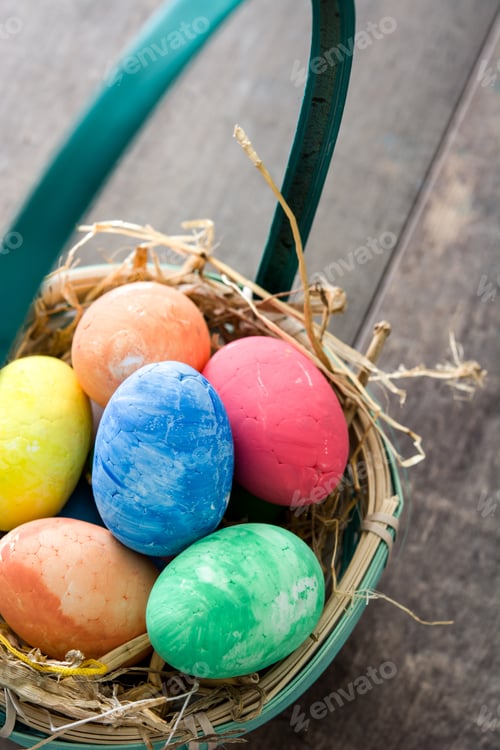Preview: Colorful easter eggs resting in a basket with straw
