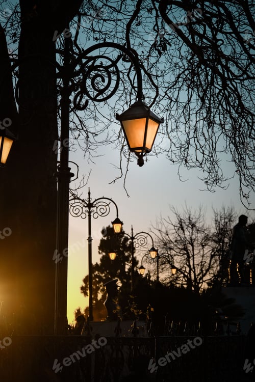 Preview: Single, streetlight illuminating against a backdrop of a stunning pink, orange and yellow sunset sky