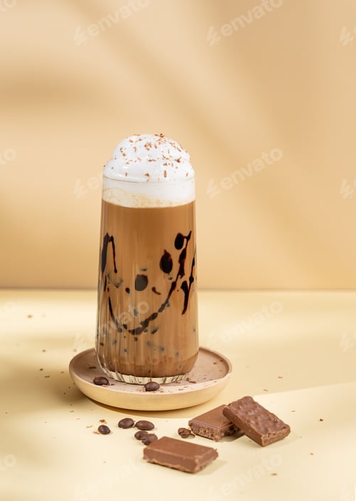 Preview: Cold chocolate coffee drink or milkshake with whipped cream in a tall glass on a yellow background