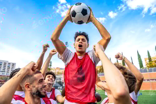 Preview: Soccer team celebrating victory with raised ball and fists