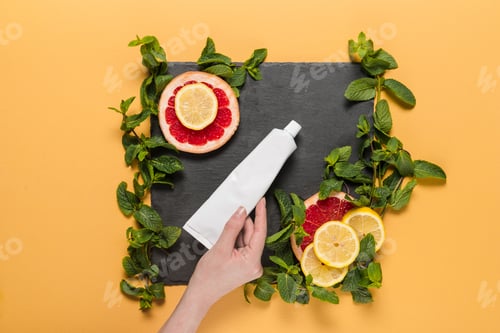 Preview: cropped view of person with organic citrus lotion with mint leaves, lemon and grapefruit slices on