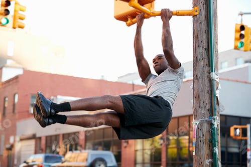 Preview: Young black man doing pull ups from crossing light in street