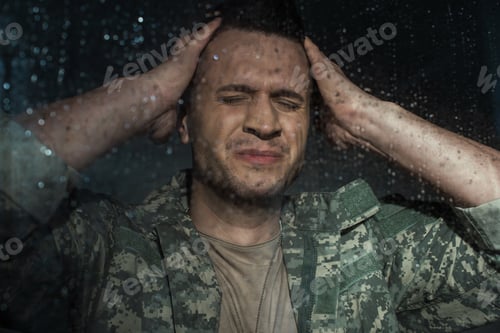 Preview: anxious serviceman in military uniform suffering from post traumatic stress disorder while standing