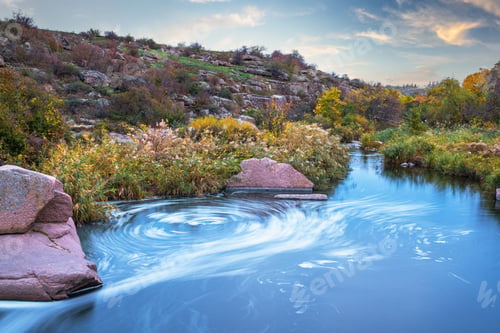 Preview: Stream runs among white wet stones covered with grass in golden autumn