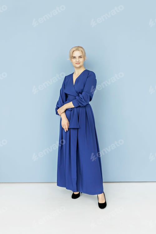 Preview: Young beautiful blonde in blue evening dress .Woman against blue background