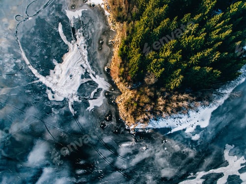 Preview: Aerial view of the winter snow forest and frozen lake from above captured with a drone in Finland.
