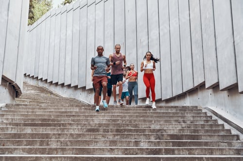 Preview: Full length of people in sports clothing jogging while exercising on the steps outdoors