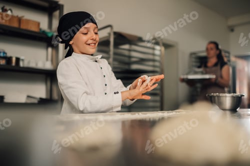 Preview: Young girl chef smiling while cleaning hands from cream cheese in kitchen.