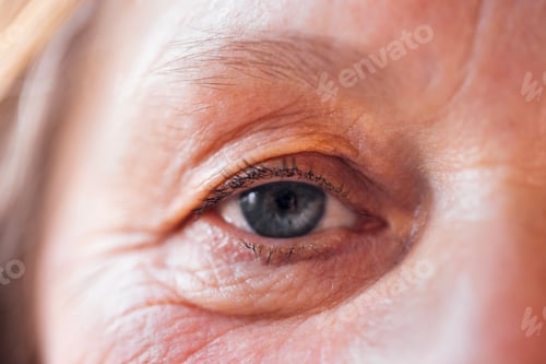 Preview: Close-up of an elderly woman blue eye. The face of a mature lady with facial wrinkles and no makeup.