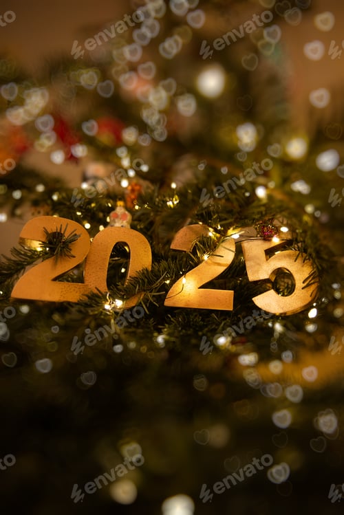 Preview: Vertical Golden 2025 with bokeh ornament on decorated Christmas tree, illuminated by warm lights