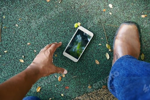 Preview: POV shot of hand picking broken smart phone from a floor