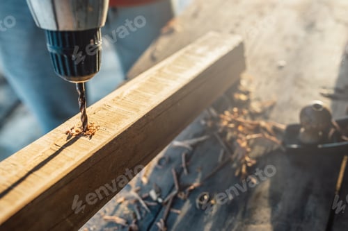 Preview: worker drills a hole in the bar with a screwdriver connect making furniture