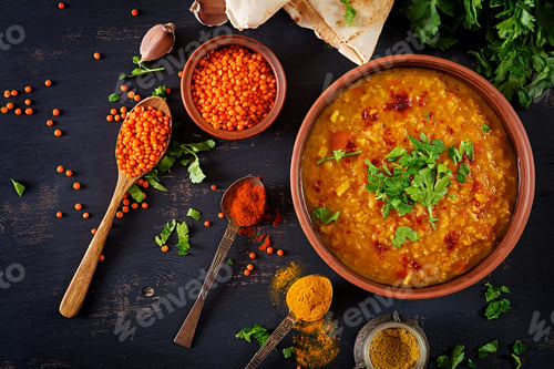 Preview: Indian Dhal spicy curry in bowl, spices, herbs, rustic black wooden background.