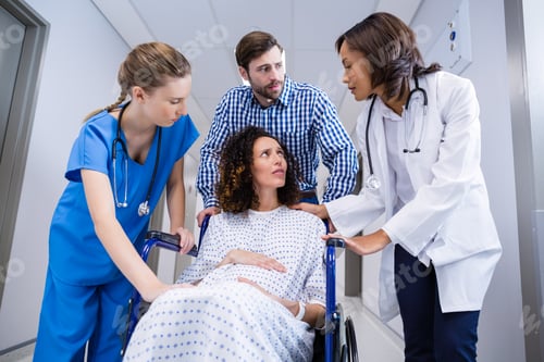 Preview: Doctors and man comforting pregnant woman in corridor