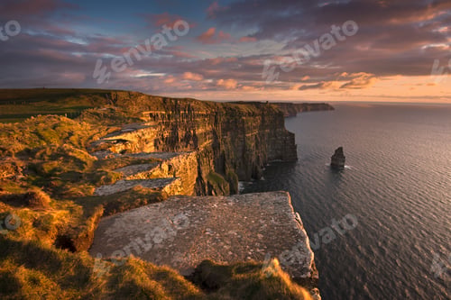 Preview: Golden sunset casting warm hues over majestic seaside cliffs