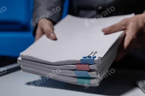 Preview: An employee was tidying up a pile of documents piled on his desk before returning home from work, A